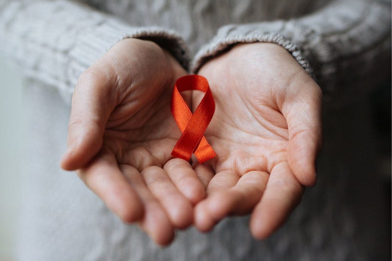 Red AIDS ribbons on the cupped palms of two hands