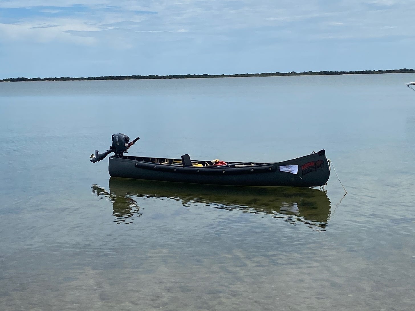 The Radisson canoe on a calm body of water and an outboard motor attached to it.