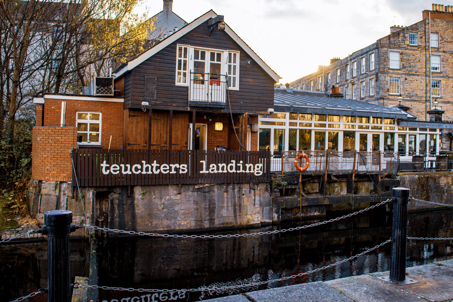 The Teuchter's Landing pub with the sign outside, reflecting in the water