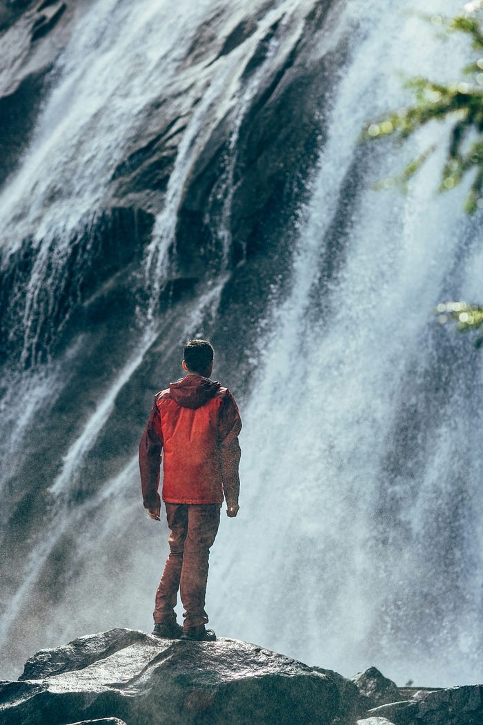 Man standing in front of a waterfall.