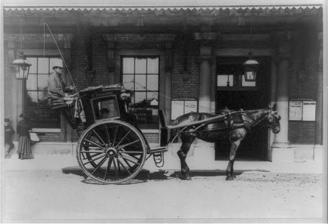 black and white photo of a horse and small cab in London