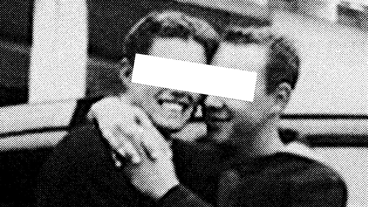 A grainy black-and-white image of two men embracing with a white rectangle covering their eyes