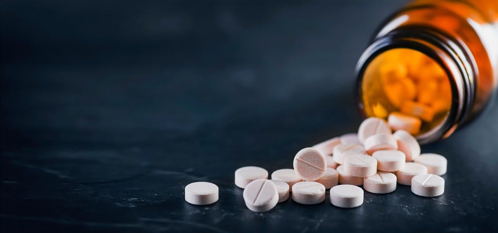 Close-up view of white medical pills and a bottle on a black background Close-up view of white medical pills and a bottle on a black background