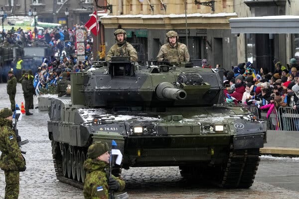 Two soldiers stand in an army tank as it rolls down a street in Tallinn, Estonia.