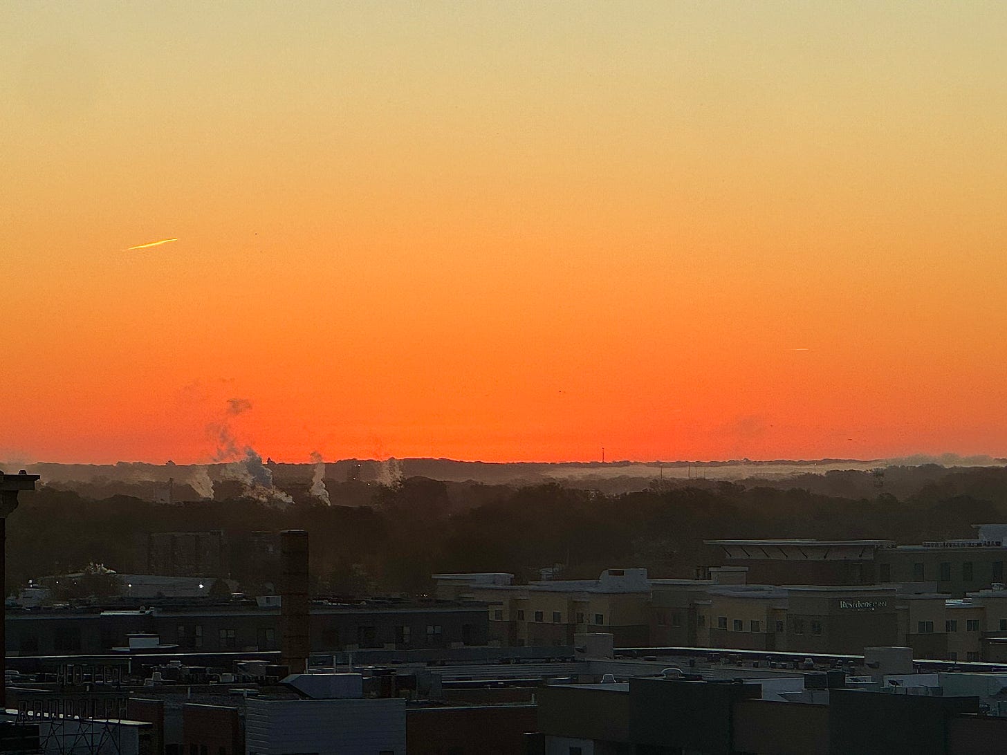 Sunrise with contrails and smokestacks