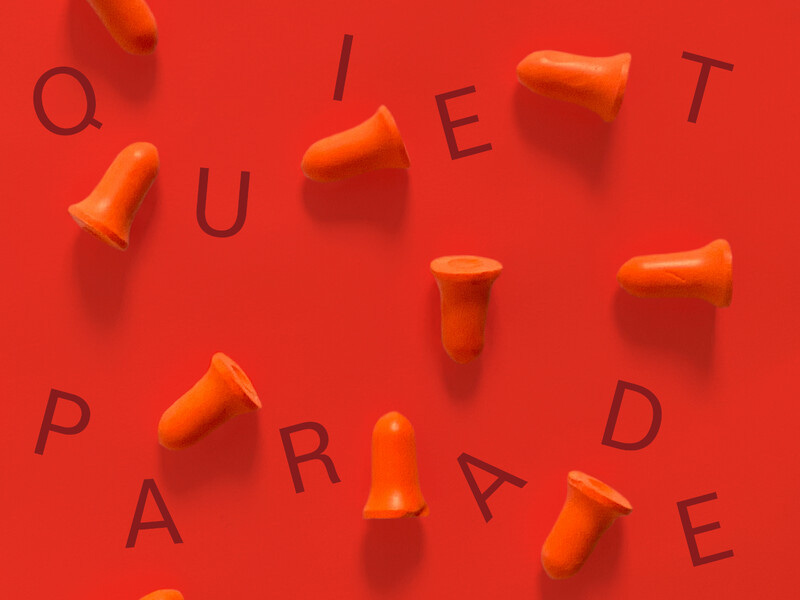 Orange earplugs and the letters “QUIET PARADE” are scattered at various angles against an orange background.