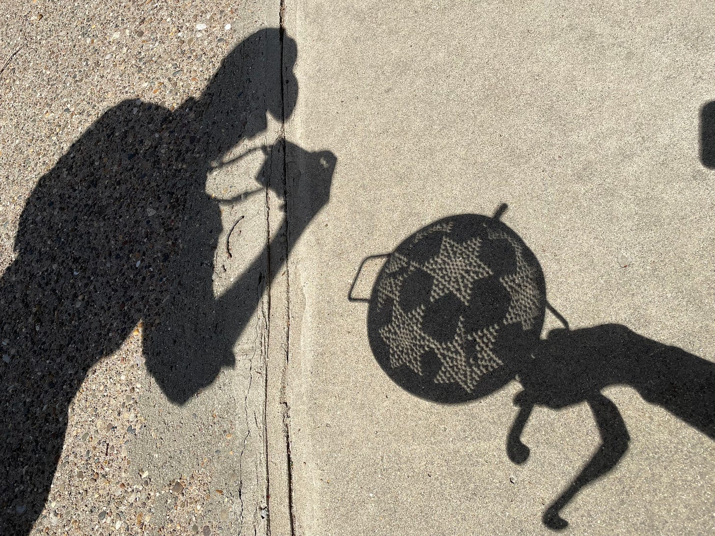 Shadows of a man taking a picture and a hand holding a colander