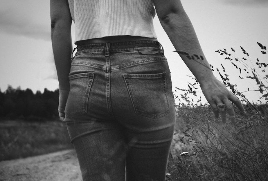 grayscale photo of woman in white tank top and black denim jeans