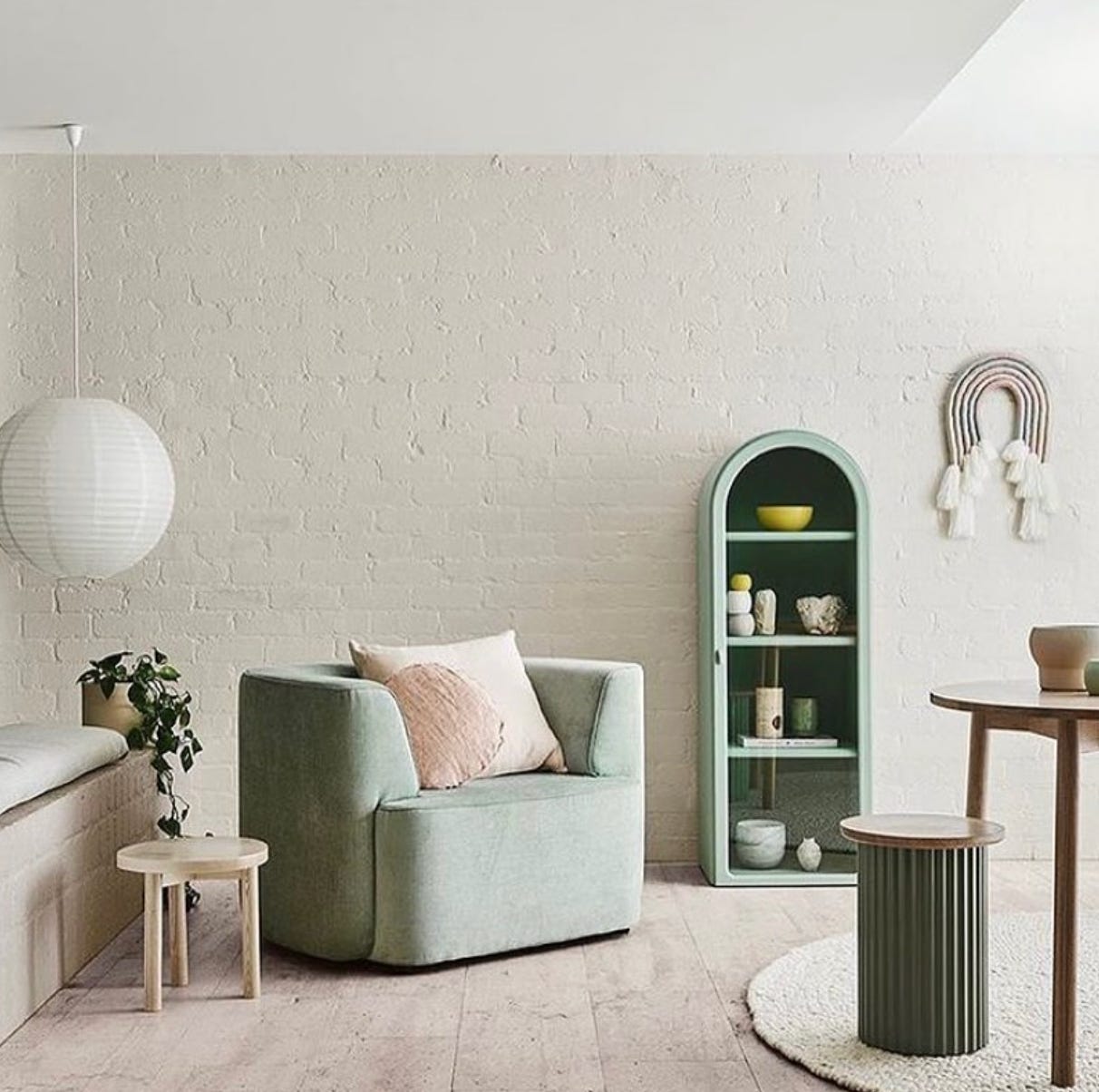 neutrally painted room with soft green armchair and dusky pink cushion