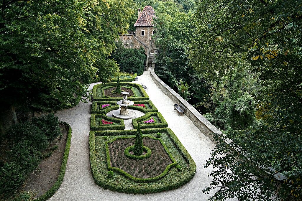formal garden with a white statue in the center of topiary