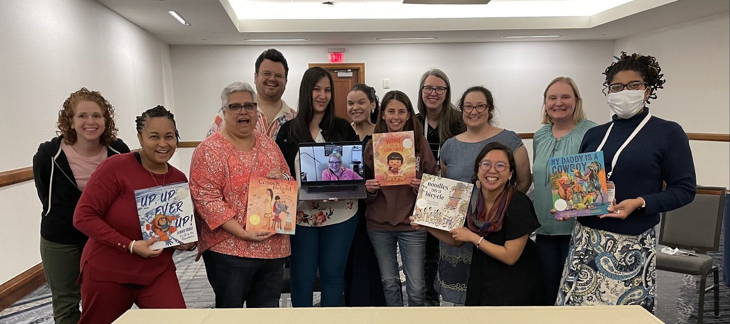 Members of the Caldecott Medal selection committee pose with a collection of picture books