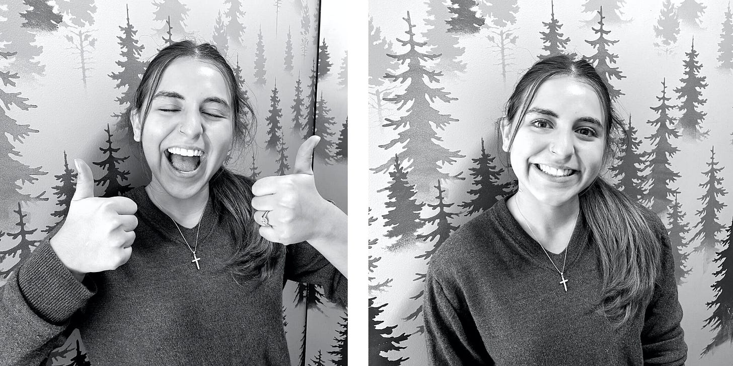 Side by side black and white photos of a young woman in a sweater standing in front of a wall with stenciled trees. In the left she smiles wide and gives two thumbs up with her eyes closed. In the right she smiles straight at the camera. Her hair is pulled in to a pony tail draped over her left shoulder.