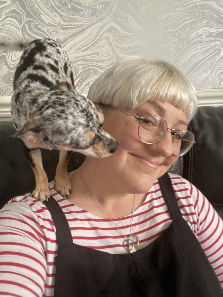 A blonde woman with a chihuahua puppy on her shoulder