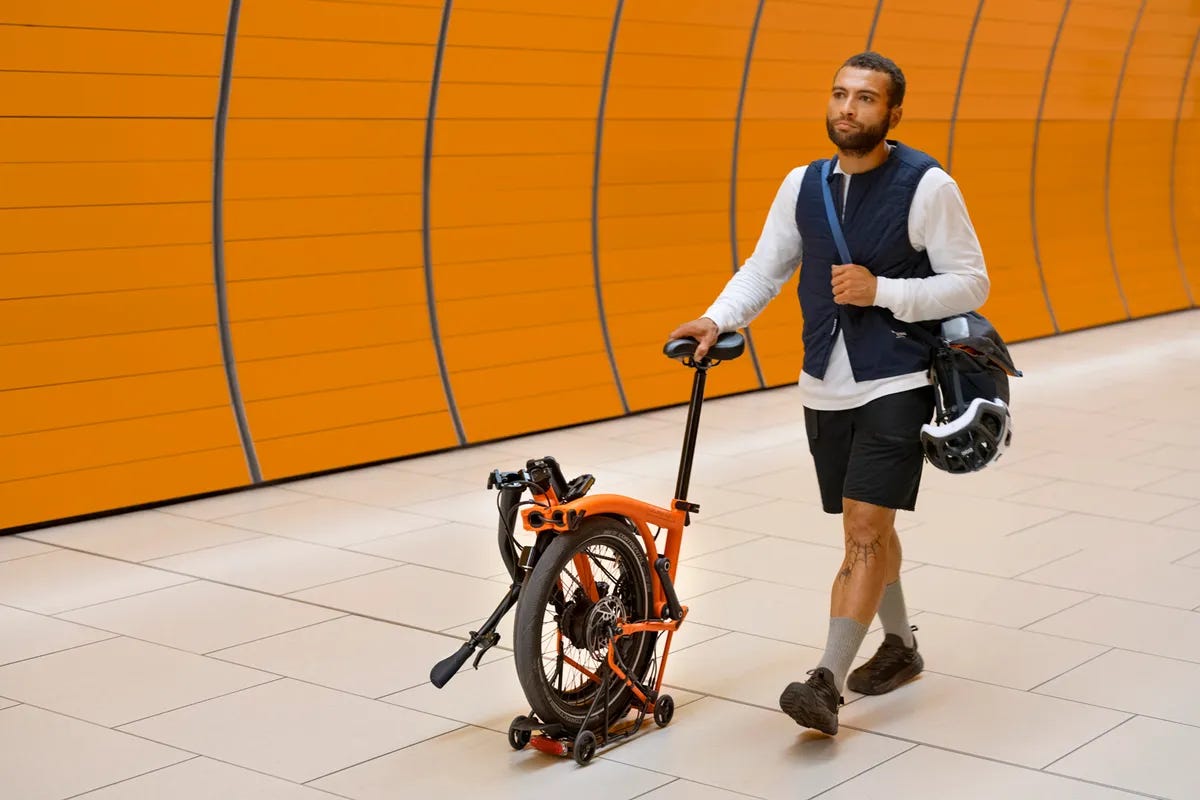 Man pushing Brompton G Line folding bike along concourse.