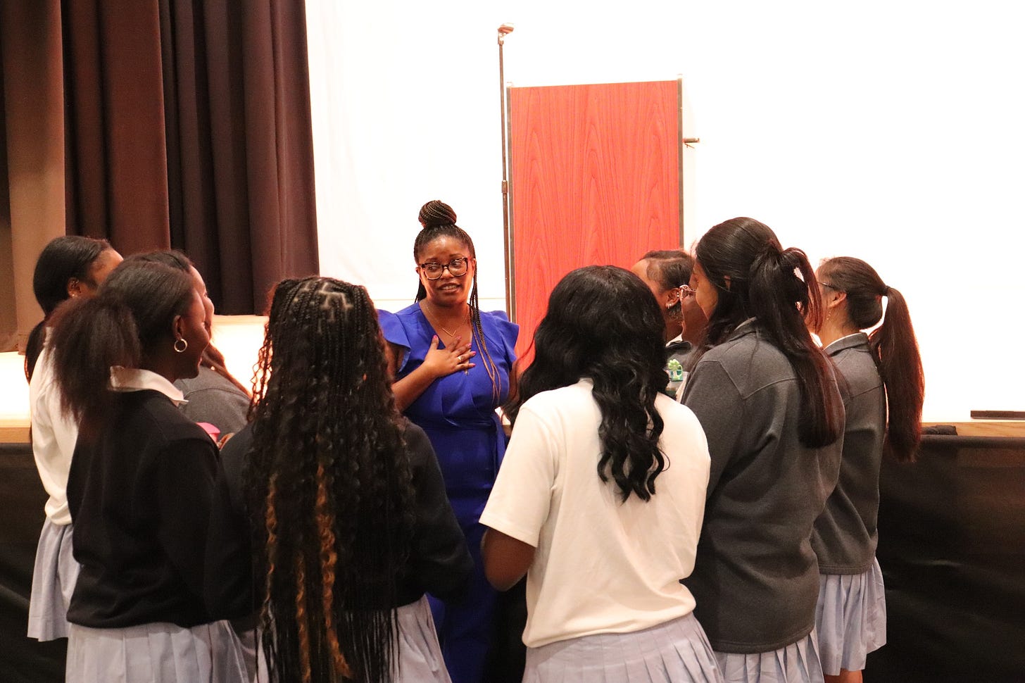 Group of Catholic high school girls surrounding a Black woman