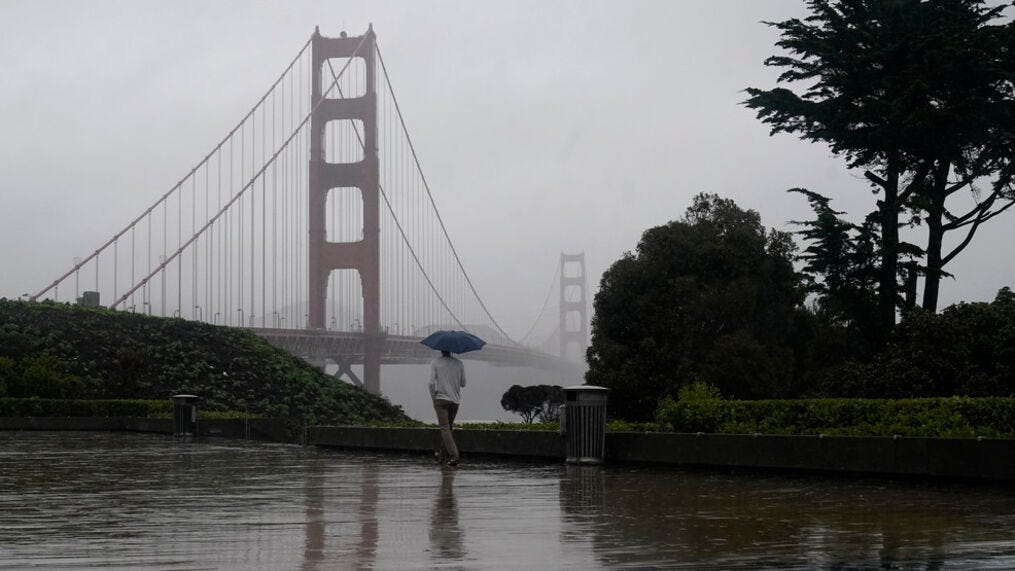 A pedestrian carries an umbrella while walking toward a path in front of the Golden Gate Bridge in San Francisco, Wednesday, Jan. 11, 2023. (AP Photo/Jeff Chiu)