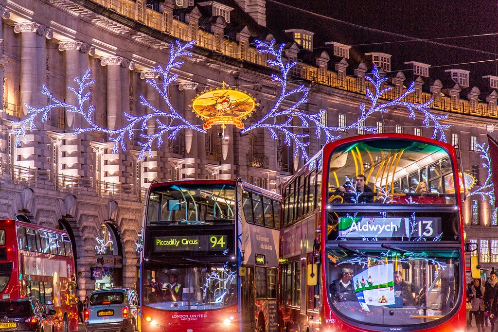 Two London buses passing under Christmas lights hanging between Georgian terraces in Central London at night