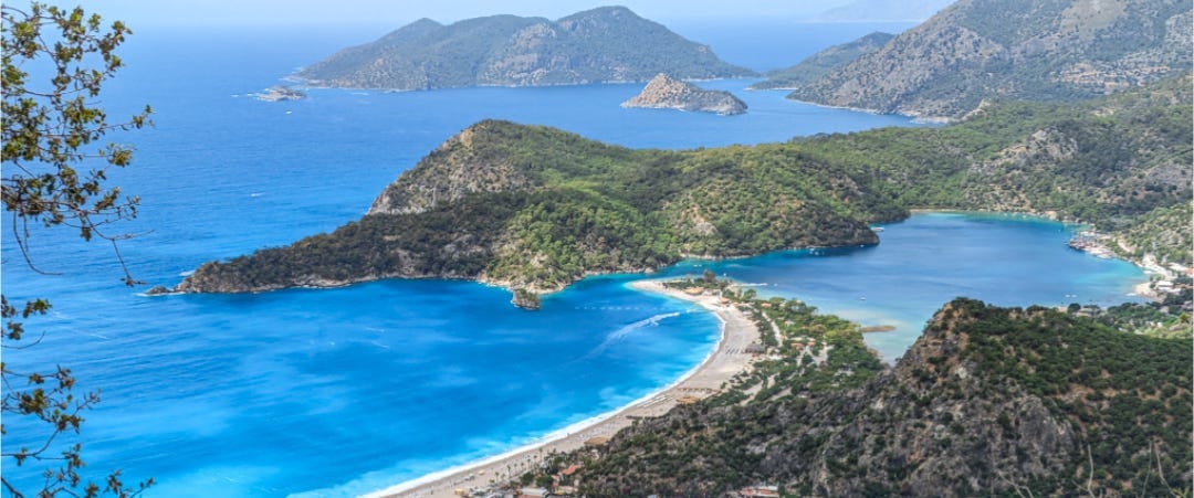 The very blue Blue Lagoon as seen from above. The rest of the coast is green hills and more vivid blue water. 