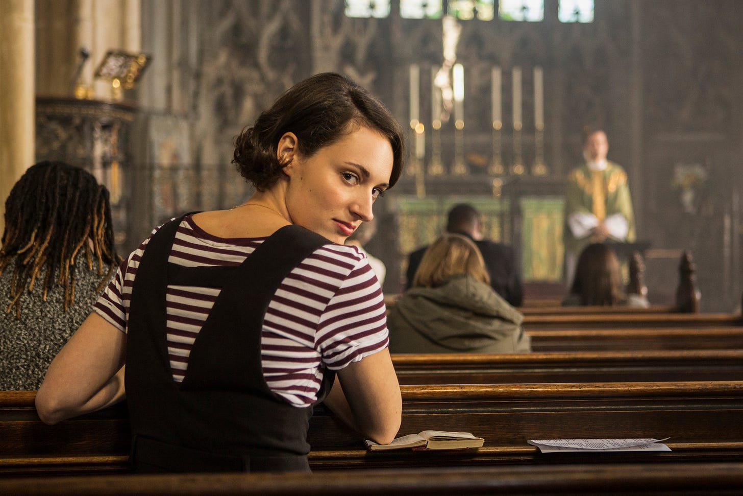 Fleabag praying in a church, but sharing an intimate moment with the viewers.