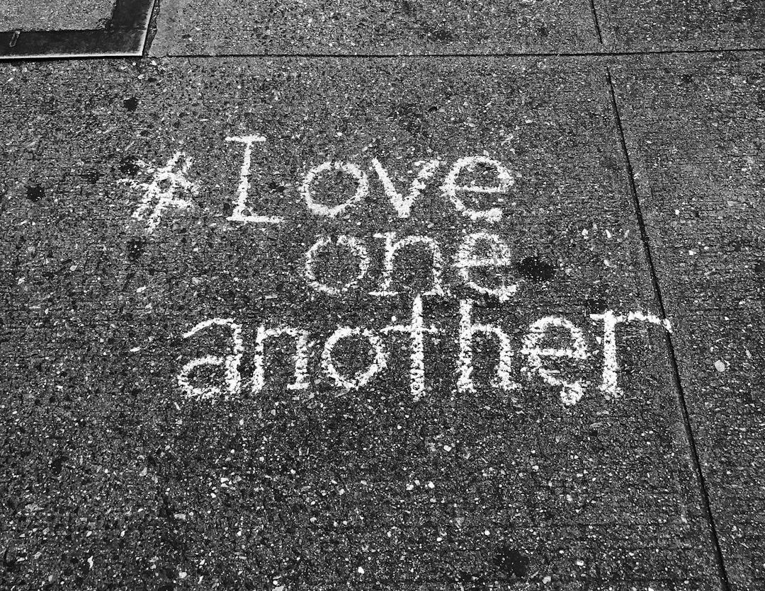 love one another chalk written on concrete floor