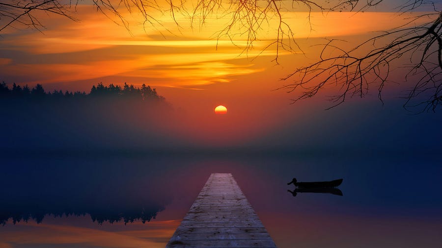 A sunrise over a lake with a canoe