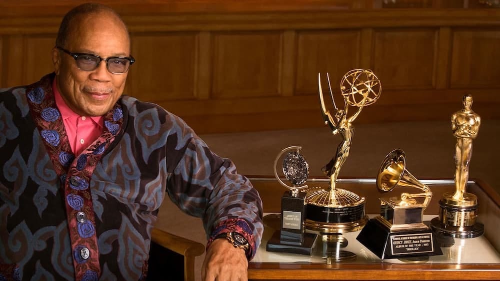 Quincy Jones sitting next to some of his many awards and trophies