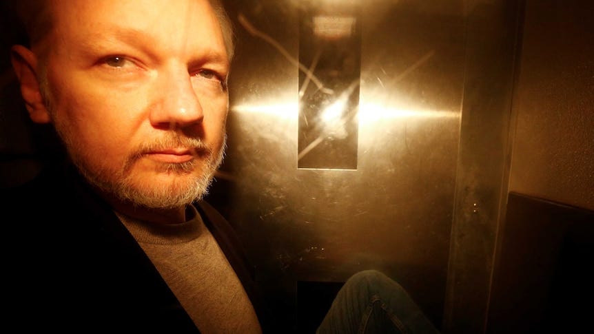 Julian Assange seen through the window of a police van.
