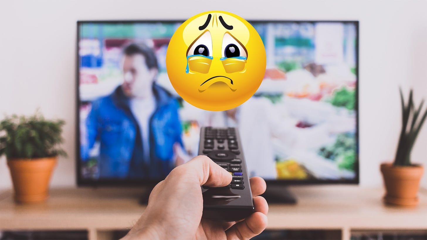 Una mano sosteniendo un mando de televisión que apunta a una televisión y un emoji triste