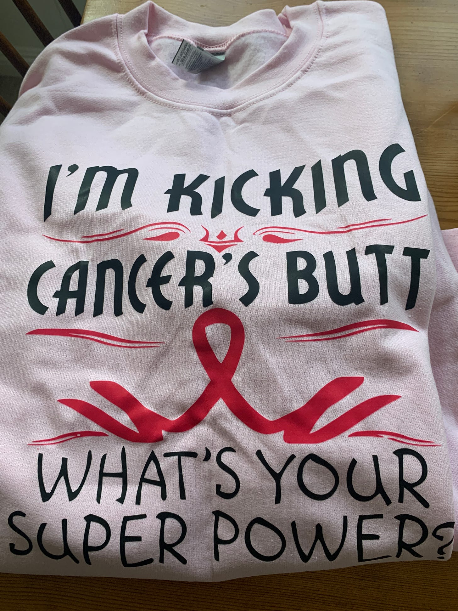 Pink sweatshirt that reads I'm kicking cancer's butt, what's your superpower?