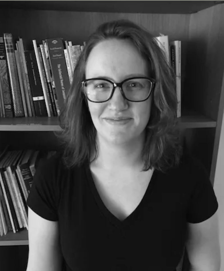 author photo of writer Kate Partridge: a white woman in glasses smiles in front of a bookshelf