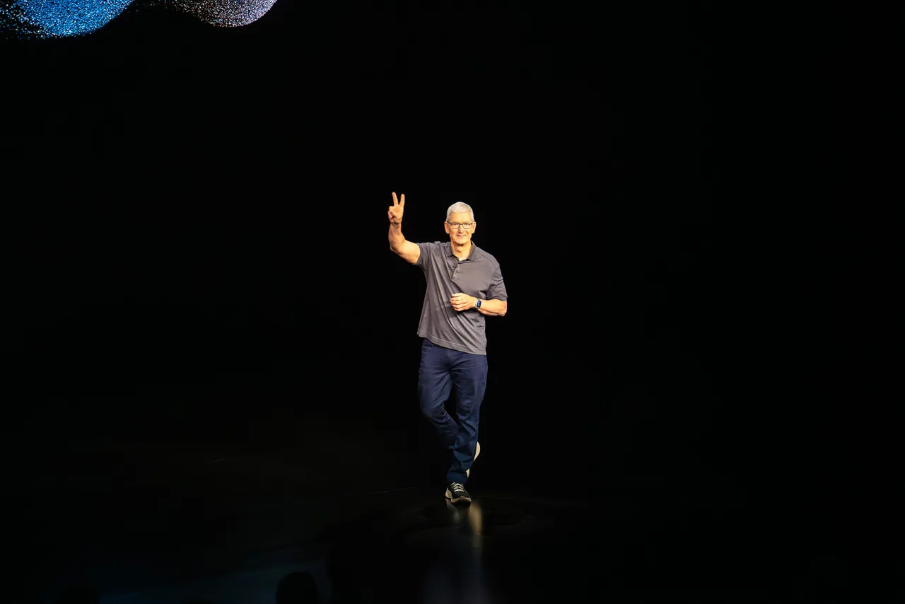 Tim Cook em um palco fazendo o sinal de V