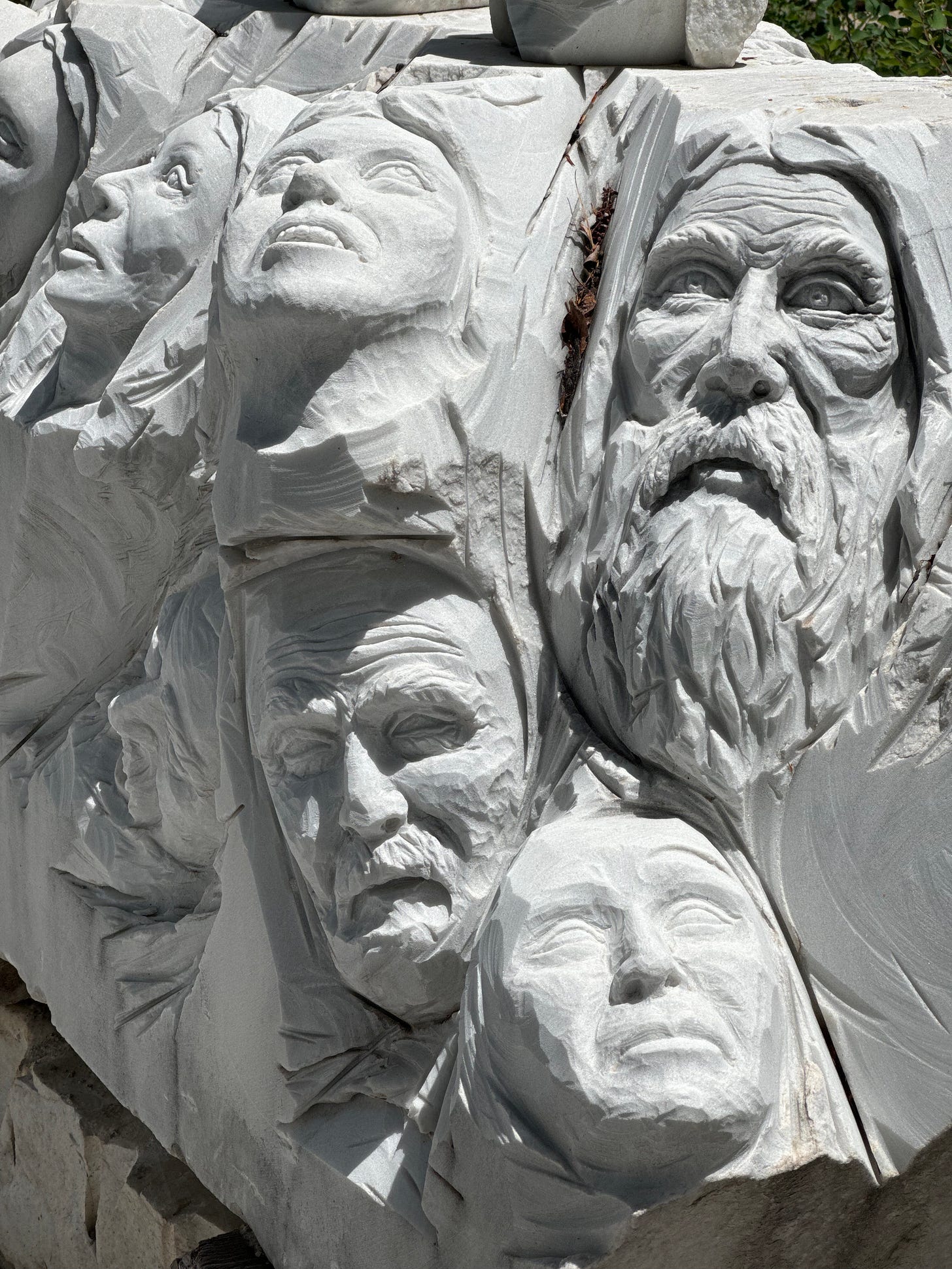 Large block of marble carved with many faces