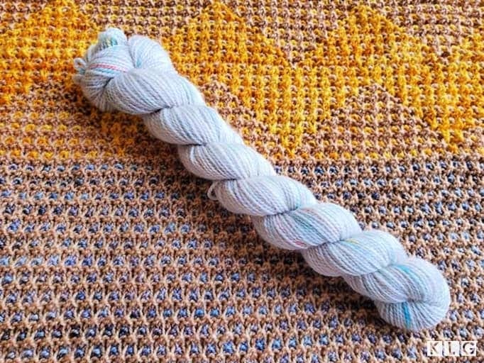 Koigu KPPM hand painted yarn in white with highlights of turquoise and reds