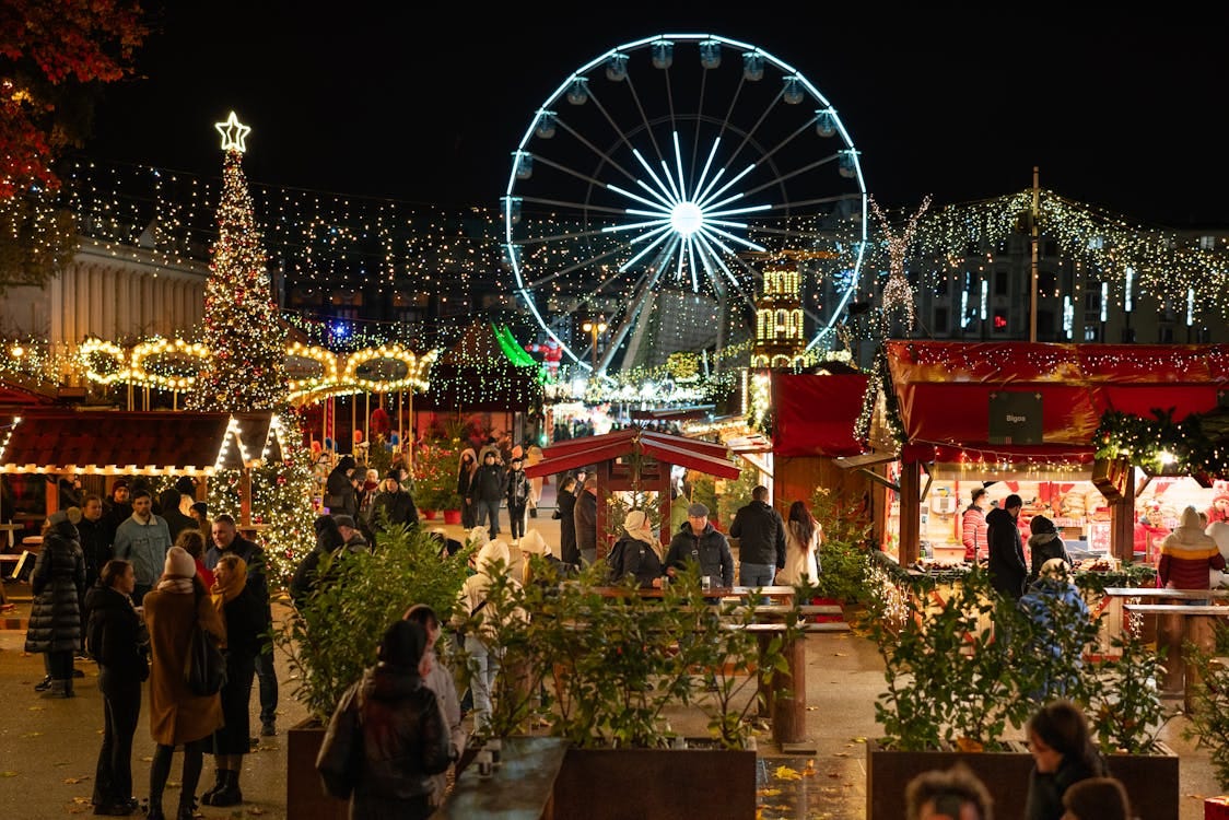 Free Festive night scene at Poznań's Christmas market featuring a ferris wheel and illuminated stalls. Stock Photo