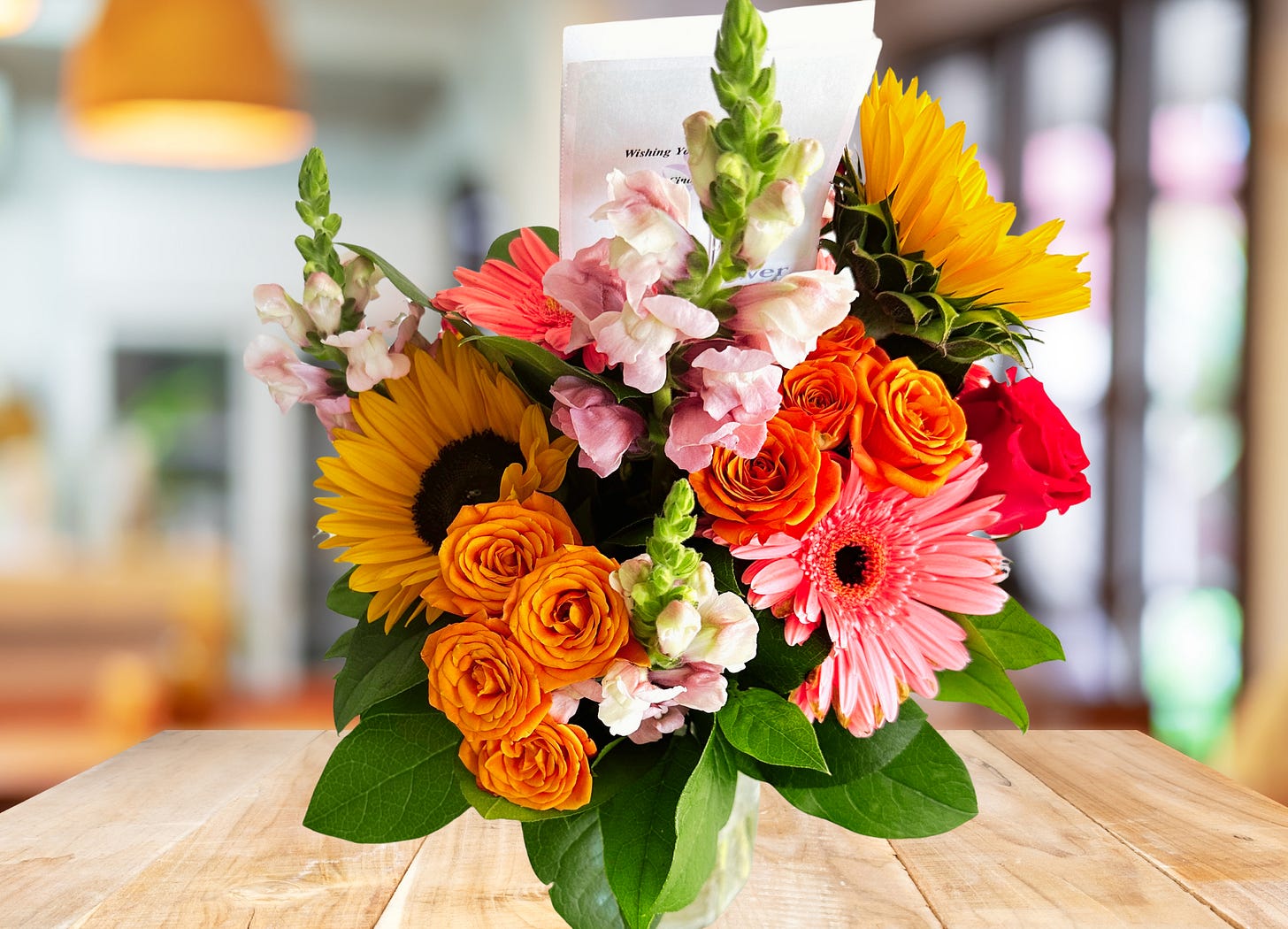 Bouquet of flowers with sunflowers, roses and snapdragons on kitchen table