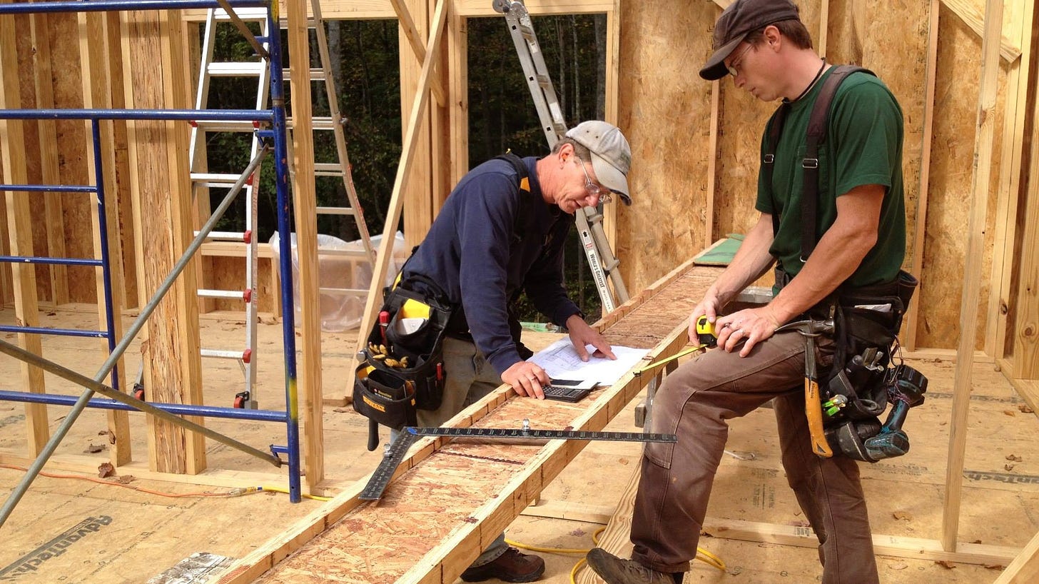Two construction workers framing a house.