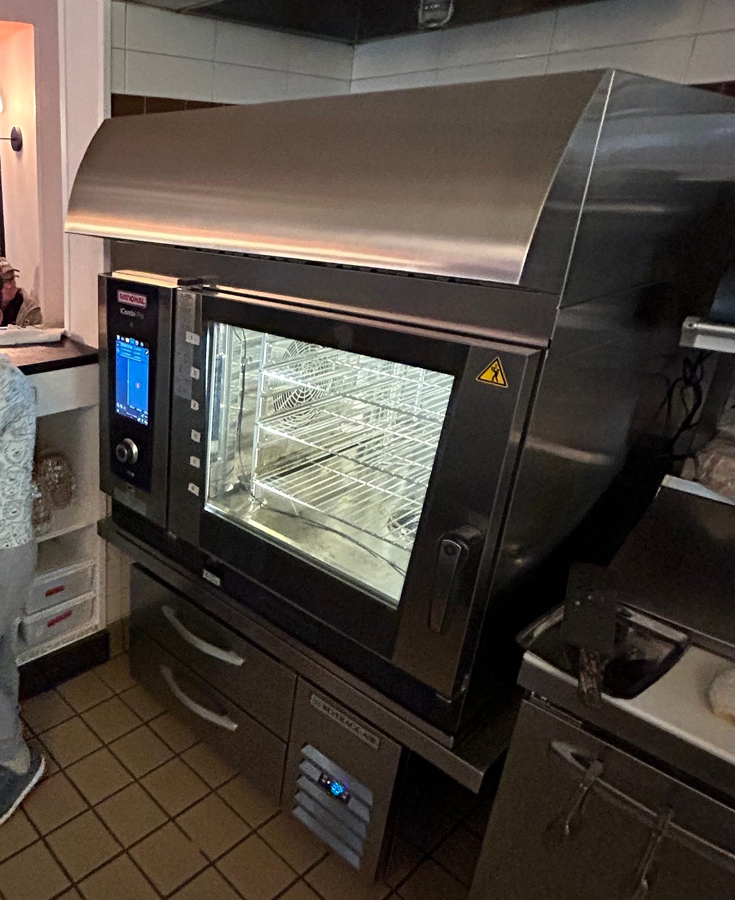 A large industrial oven with a touch screen on the side, within a kitchen
