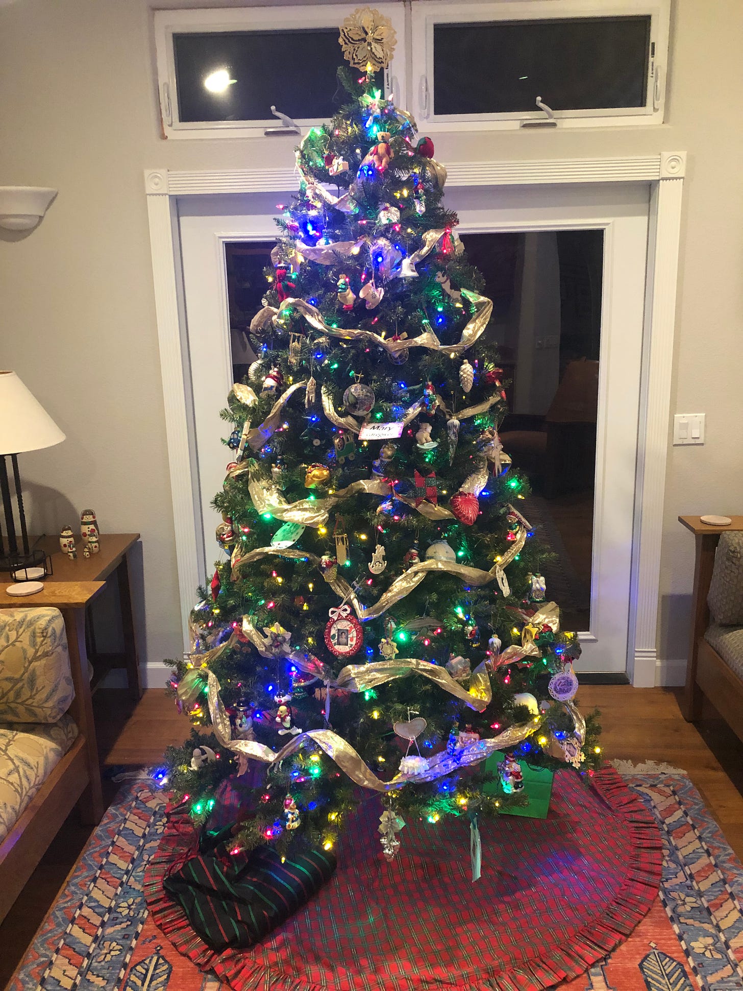 A Christmas tree with multi-colored lights, a variety of ornaments (including handmade) and gold garland.