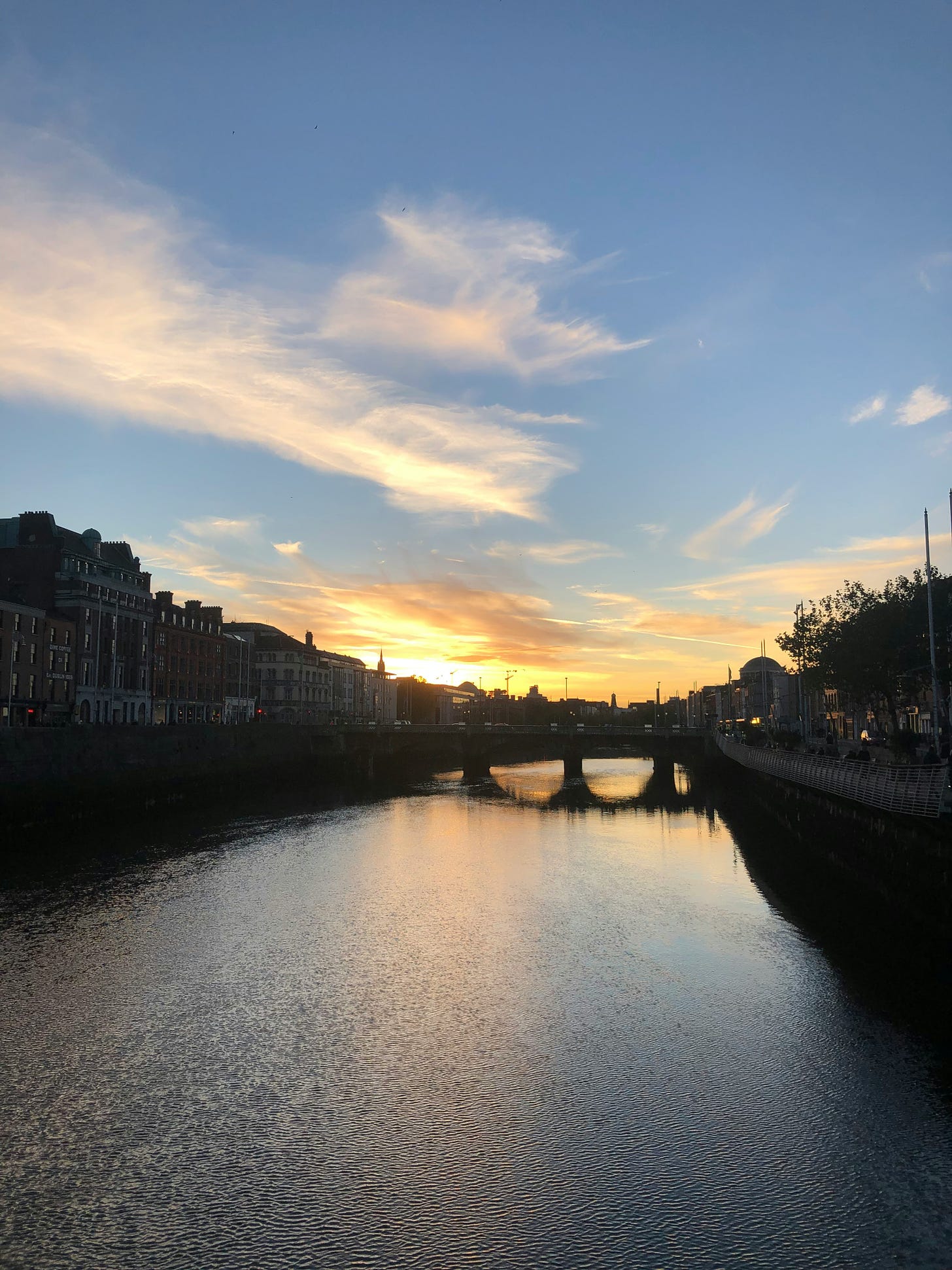 The sun rises over Dublin city, the Liffey reflecting the morning sun and clouds. 