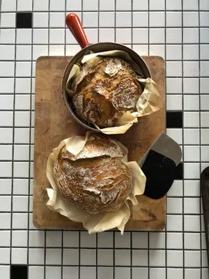 Two boules of sourdough bread atop a wooden cutting board.