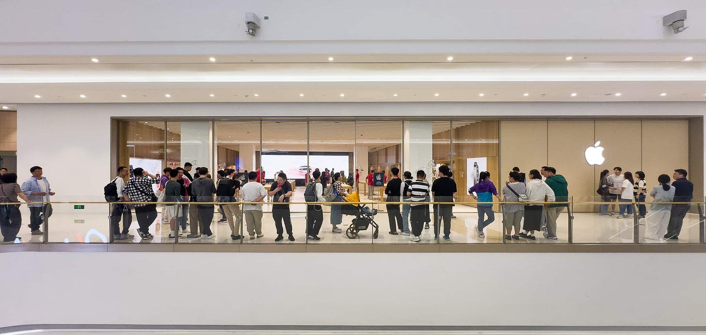 The exterior of Apple MixC Wenzhou. Customers are lined up outside the doors.