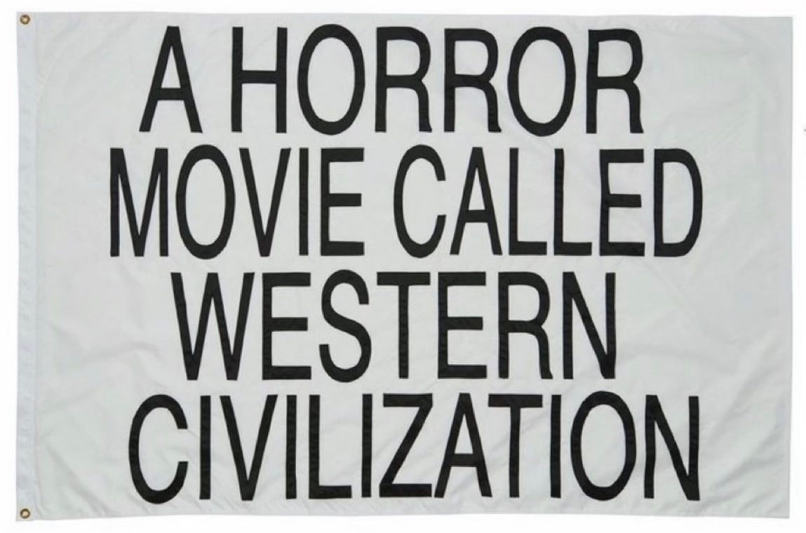 a white flag with black text in capital letters that reads: “A horror movie called western civilization.” the flag is laid flat on a white surface.