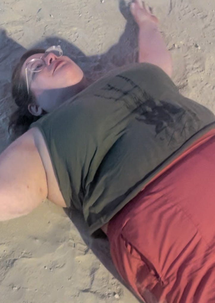 A pic of me -- an overweight white woman in a tank top, pink pants, and glasses -- lying in the dust and making a dust angel