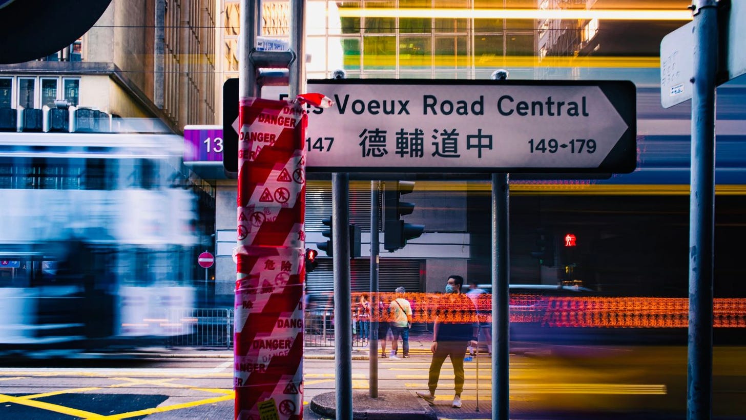 Photo of a tram speeding behind a street sign Des Voeux Road Central