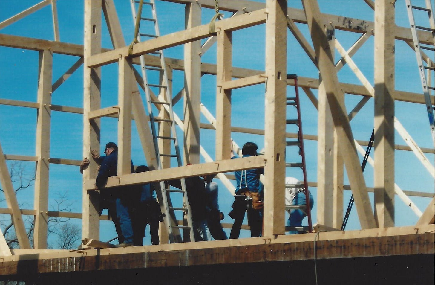 Workers beginning to frame a barn in post and beam style
