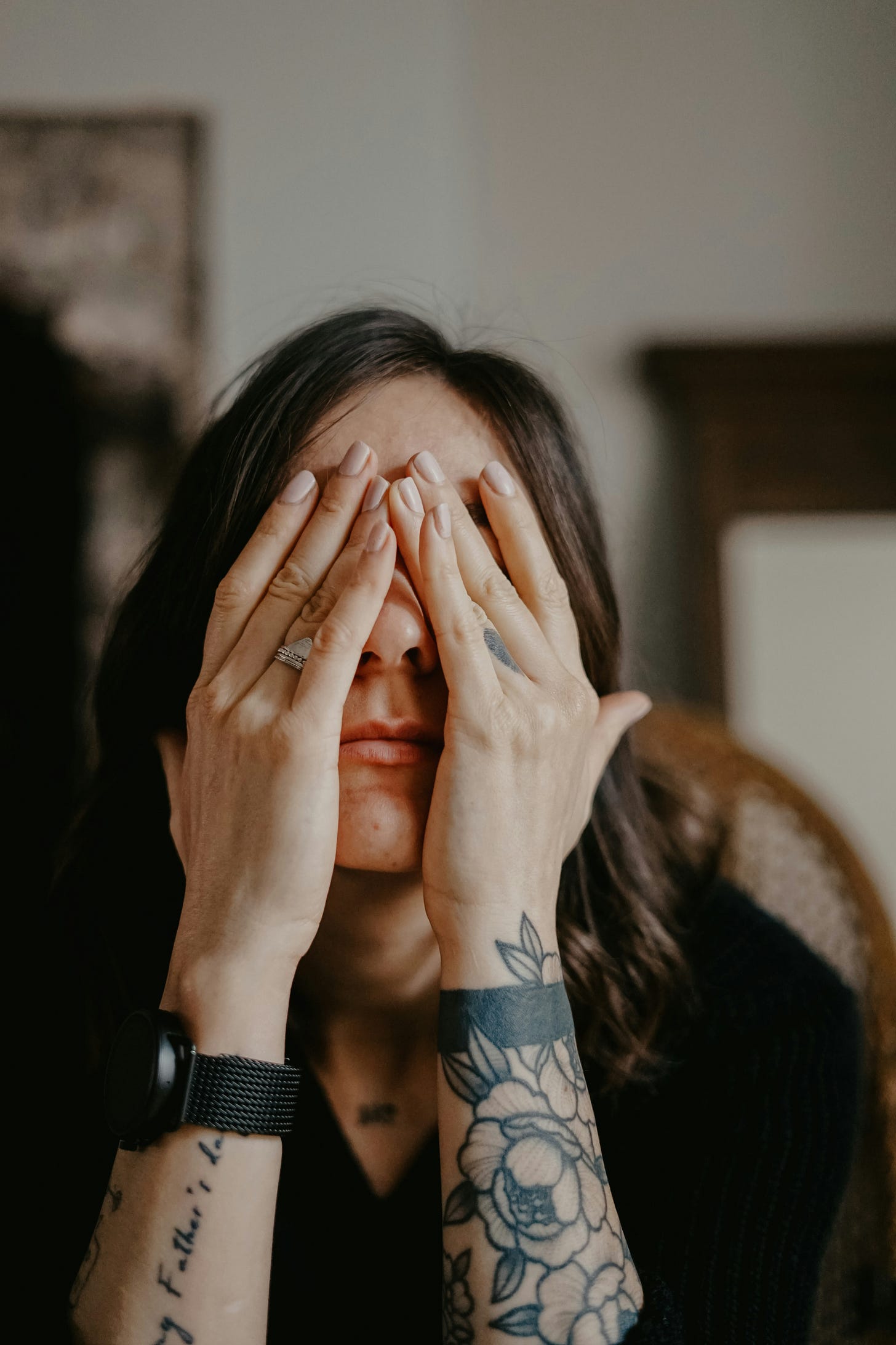 Woman with hands over her eyes as if feeling overwhelmed