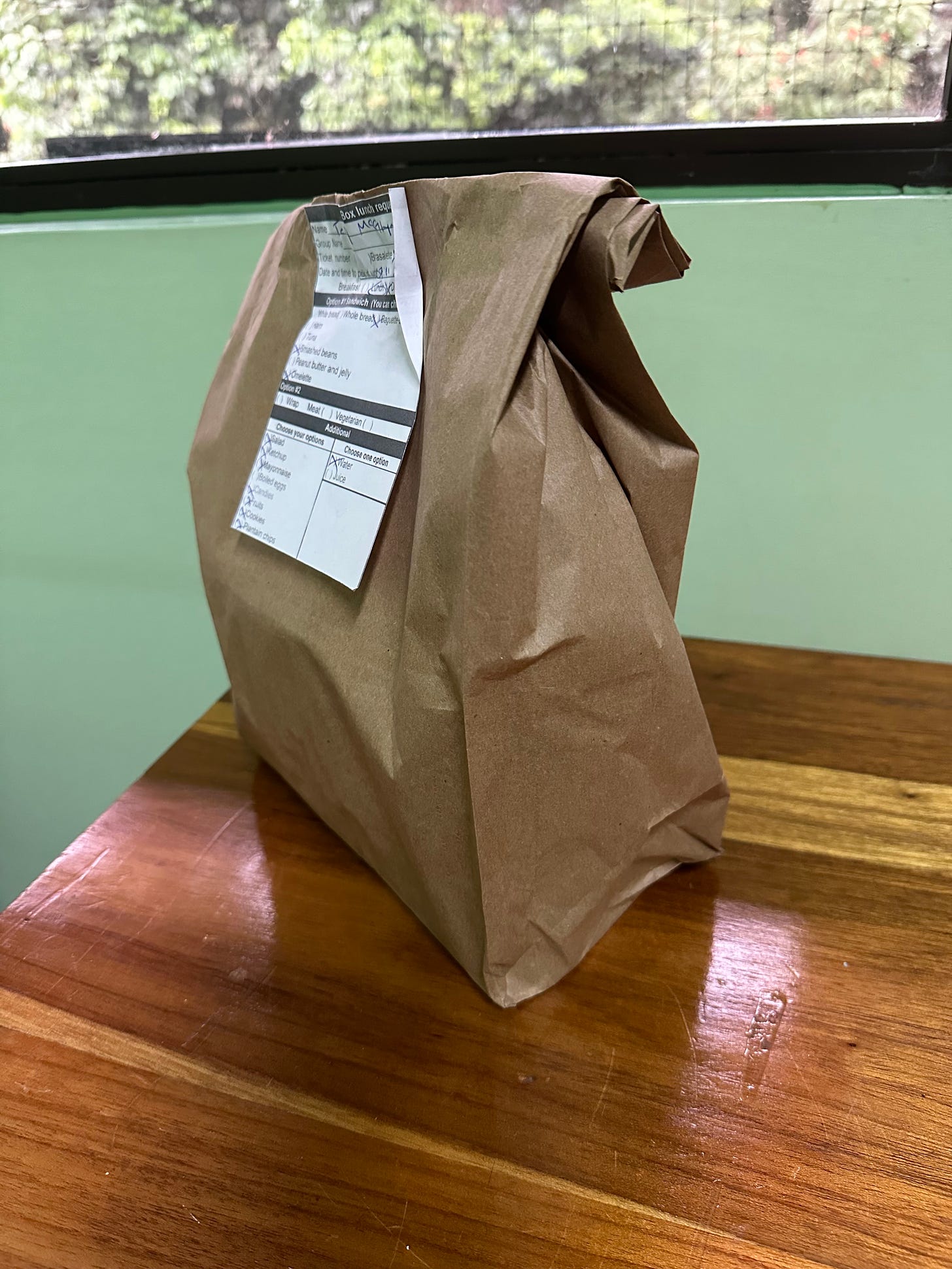 a brown paper bag filled and closed with a staple, an illegible order slip on it