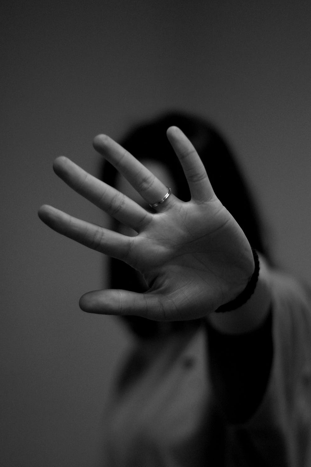 A person holds their hand in front of their face in a “stop” gesture.