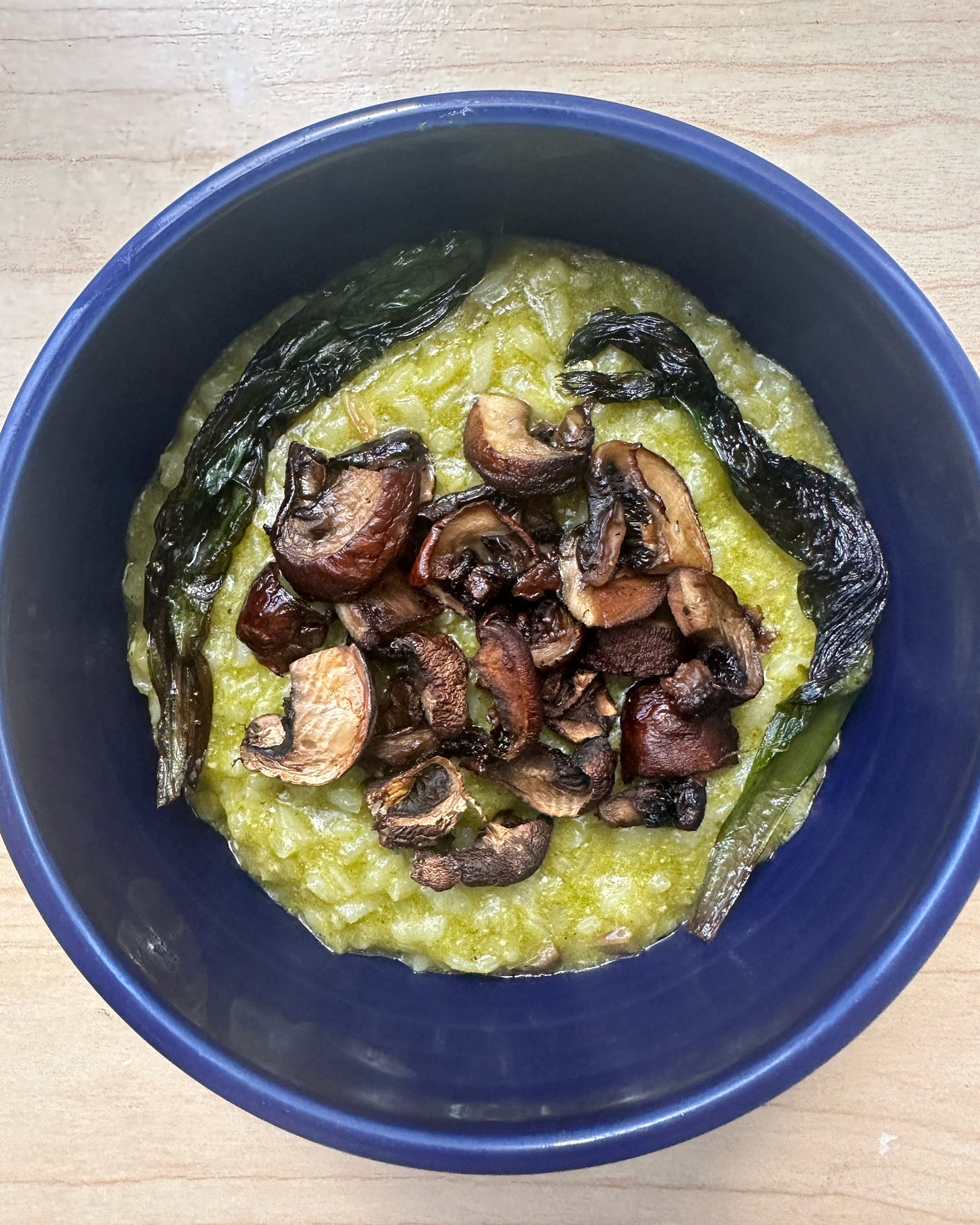 A bowl of green ramp risotto with crispy ramps and mushrooms.