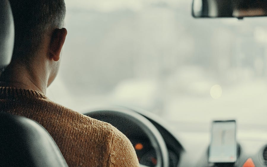 Person at the driving wheel of a car.